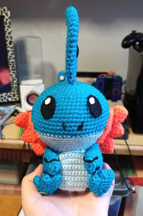 A crocheted plushie of the pokemon Mudkip.
