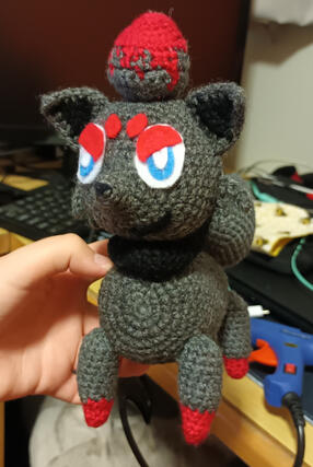 A crochted plushie of the pokemon Zorua