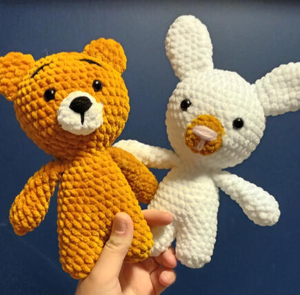 Two crocheted plushies, one brown bear and one white rabbit.
