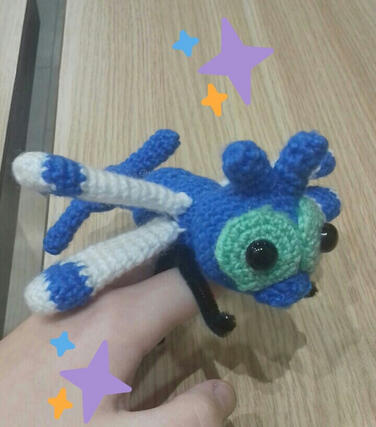 A crocheted plushie of the shiny version of the pokemon Yanma.