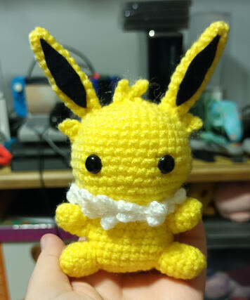 A crocheted plushie of a chibi version of the pokemon Jolteon
